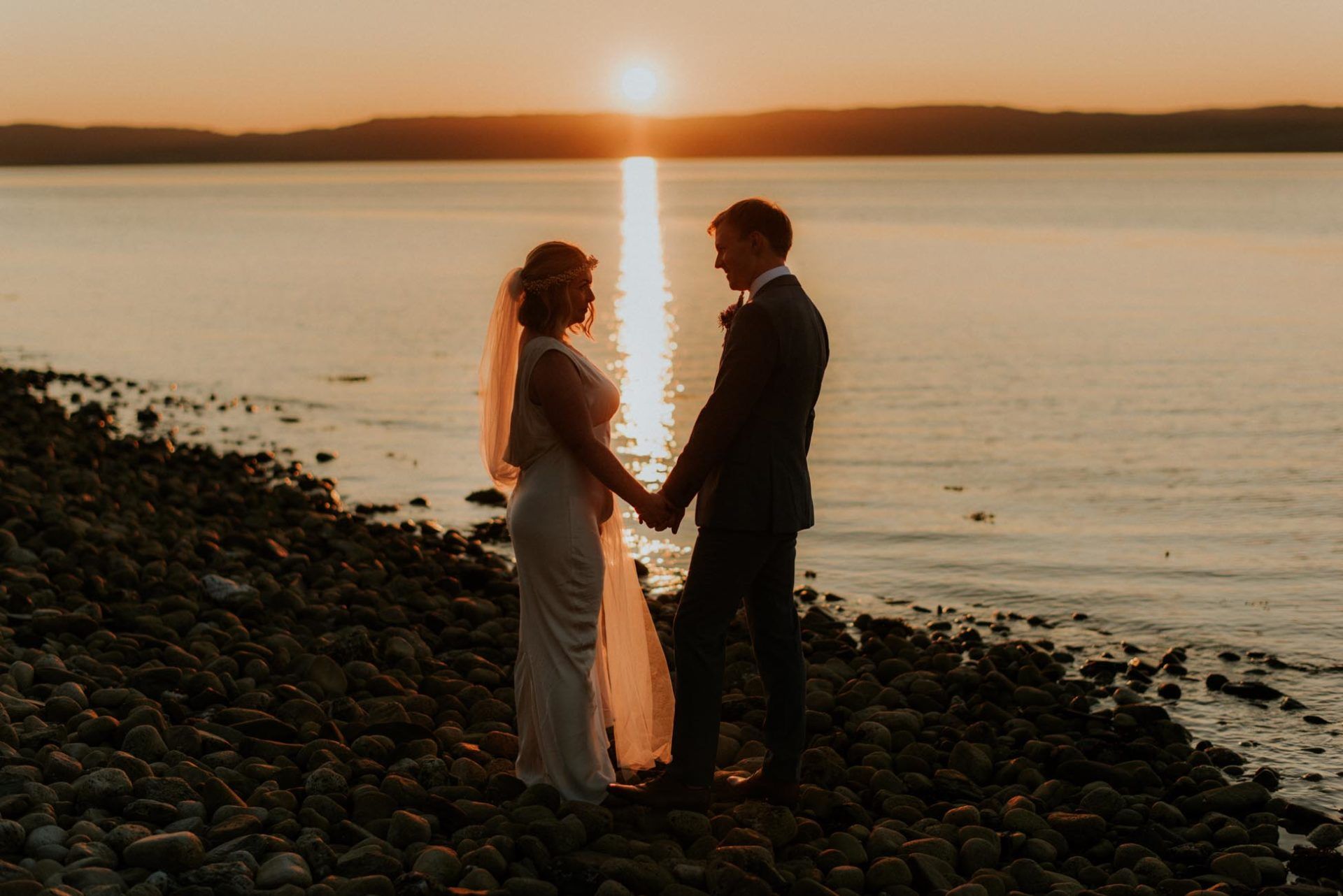 bride and groom with sun setting in-between then